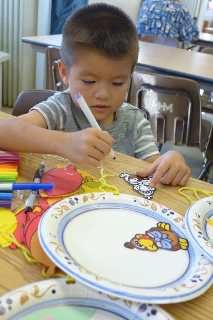 A Dharma School student making Thanksgiving decorations